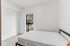 Bright and airy bedroom with a large window and a serene view, featuring minimalist decor and a comfortable bed.