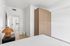 Bright, minimalist bedroom with stylish wooden wardrobe and elegant decor for contemporary living.