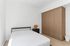 Cozy modern bedroom featuring a minimalist black bed frame, sleek wooden wardrobe, and stylish lamp, ideal for serene living.