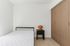 Chic minimalistic bedroom featuring sleek bed, modern nightstand with unique lamp, and elegant built-in closets.