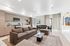 Modern open-plan living space with cozy sofa, sleek kitchen, and dining area, bathed in natural light.