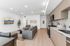 Modern open-plan living room and kitchen with sleek wooden flooring, stylish gray sofa set, and contemporary artwork enhancing the elegant space.