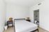 Bright, minimalist bedroom with modern design, featuring a comfortable bed, stylish side tables with accent lamps, and an en-suite bathroom.