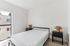 Bright and modern bedroom featuring a minimalist design with large window, sleek bed, and stylish side tables with unique lamps.