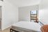 Bright and airy bedroom featuring a modern bed, sleek decor, and a window offering scenic views of palm trees.