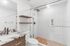 Modern bathroom featuring a sleek glass shower, stylish wood shelving, and elegant marble countertop for a luxurious feel.
