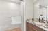 Elegant bathroom with a sleek, marble countertop and a spacious glass-enclosed shower, enhanced by soft white tiles and warm wooden cabinetry.