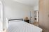 Bright and modern bedroom featuring minimalist decor, wooden wardrobe, and natural light streaming in.