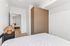 Bright and modern bedroom with sleek wooden wardrobe and stylish rattan lamp for an inviting atmosphere.