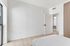 Bright, modern bedroom with large window, light wood flooring, and minimalist design.