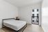 Bright and airy bedroom with modern bed frame, stylish nightstand, and large window offering a view of the cityscape.