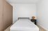 Inviting modern bedroom with a cozy bed, sleek wooden wardrobe, and charming bedside lamp, perfect for serene relaxation.