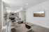 Modern apartment living room with a sleek design, cozy gray sofa, stylish coffee table, and wall-mounted flat-screen TV, adjacent to a contemporary open kitchen.