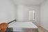 Bright and modern bedroom with a minimalist aesthetic, featuring a comfortable bed, sleek bedframe, and a stylish wicker lamp against a pristine white wall.