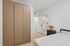 Modern bedroom with sleek built-in wardrobe, cozy bed, and adjacent bathroom boasting contemporary design elements.