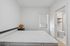 Bright, minimalist bedroom with a cozy ambiance, featuring a queen-sized bed, wicker lamp, and en-suite bathroom access.