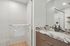 Elegant modern bathroom featuring a chic marble countertop and spacious glass shower enclosure.