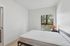Bright bedroom with a plush bed, large window view of lush greenery, and sleek minimalist decor.