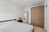 Modern bedroom with sleek wooden wardrobe and minimalist decor. Bright and airy with neutral tones and natural light.