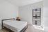 Bright, minimalist bedroom with modern bed, stylish nightstand, and a sunlit window offering a serene view.