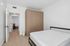 Bright bedroom with sleek fitted wardrobe, modern bed frame, and cozy wood flooring.