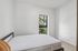 Bright, minimalist bedroom featuring a large window and serene garden view.