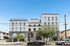 Elegant contemporary apartment building with arched windows and balconies, set against a clear blue sky.