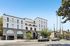 Elegant modern apartment building with a stylish facade, spacious balconies, and large arched windows, set against a clear blue sky.