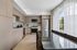 Sleek modern kitchen with stainless steel appliances, glossy dining table, and large windows offering abundant natural light.