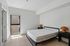 Modern, sunlit bedroom with minimalist design featuring a large bed, sleek black frame, and stylish rattan lamps on elegant side tables.