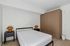 Modern bedroom featuring a minimalist bed, chic wooden wardrobe, and stylish bedside lamps in a sleek, white-walled space.