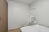Chic minimalist bedroom with elegant built-in wardrobe and a sunlit window.
