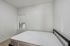 Bright minimalist bedroom with a cozy double bed and natural light from a window with a view.
