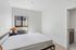 Bright and minimalist bedroom with large window, modern decor, and ensuite bathroom entrance.