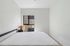 Bright minimalist bedroom with large window and modern lamp, offering a serene view.