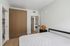 Contemporary bedroom featuring sleek wooden wardrobe, modern side table, and minimalist decor.