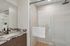 Elegant bathroom featuring a stylish marble countertop, modern dark fixtures, and a spacious glass-enclosed shower.