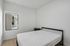 Bright and airy bedroom with minimalist decor, featuring a sleek black bed frame and contemporary lighting.