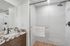 Elegant bathroom with a modern marble countertop, sleek black fixtures, and a spacious glass-enclosed shower.