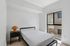 Modern bedroom with cozy bed, sleek nightstand, and sunlit window, offering a serene retreat.