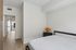 Bright and airy bedroom with modern finishes, featuring a cozy bed, stylish lamp, and smooth wooden floors, leading to a private balcony entrance.