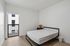 Bright and modern bedroom featuring a cozy bed, sleek bedside table with a chic lampshade, and a large balcony window enhancing natural light.