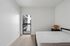 Contemporary bedroom with sleek design featuring a cozy bed, chic side table with a stylish lamp, and access to a private balcony.