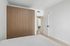 Modern bedroom featuring sleek wooden wardrobes, minimalist decor, and a welcoming entrance.