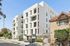 Contemporary apartment building showcasing sleek architecture with spacious balconies, located on a charming street with landscaped surroundings.