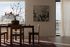 Elegant dining room with modern wooden furniture, chic wall art, and a large vase with blossoming flowers, bathed in natural light from expansive windows.