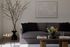 Elegant living room with a modern gray sofa, stylish artwork, and chic floral arrangements creating a cozy ambiance.