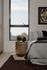 Cozy bedroom with elegant decor, featuring a plush bed, stylish side table with a decorative lamp, and a large window providing ample natural light.