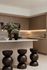 Modern kitchen with elegant wooden cabinetry, a marble countertop, and designer stools, complemented by a vase of vibrant flowers.