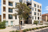 Modern apartment building with sleek architecture, large windows, and lush greenery, offering an inviting and contemporary urban living experience.